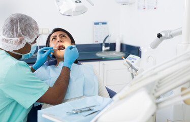 Hispanic woman receiving professional teeth treatment in dental office ..
