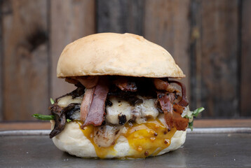 Traditional burger made with bread, bacon, cheddar cheese, lettuce, tomato and mustard.
