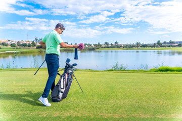 Man playing golf at golf club by a lake, driver, iron, pitching