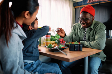 A multiracial family is having lunch in a van.