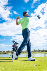 Obraz premium A player playing golf on the golf course, hitting the ball next to a lake, vertical photo