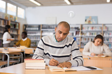 Portrait of young adult man studying in at public library