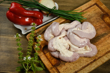 Cow bowels presented on a wooden board with ingredients, ready to grill