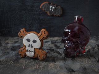 Halloween greeting card with red wine in a glass skull and a gingerbread in the shape of a skeleton