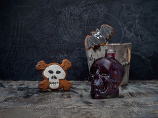 Halloween greeting card with wine in a glass skull and gingerbread in the shape of a skeleton and a bat