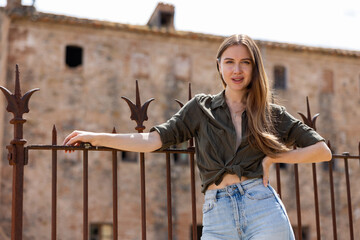 Portrait of sensual young attractive woman posing near fence against old abandoned building