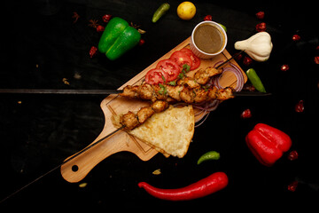 Grilled Seekh Kabab served on wooden plater with sauces on black background