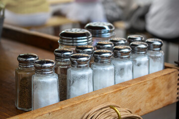 salt and pepper rows at a restaurant ready to be placed on empty tables for dining customers