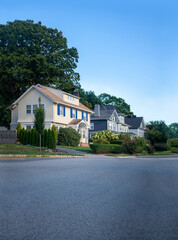 Fototapeta na wymiar suburban homes houses on a walkway street with grass, trees on a blue sky day