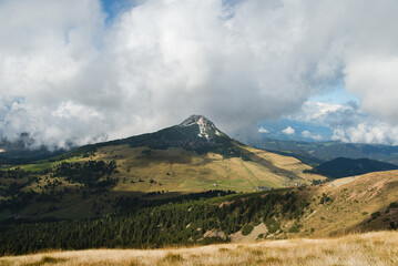 Naklejka premium Scenic beautiful alpine landscape with peak rocky mountains in dense low clouds in morning sunlight.