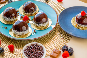 cupcake with chocolate cream. Chocolate round cake with raspberry set on a blue plate and chocolate decor on a beige table.Berry dessert.Delicate airy cake souffle.Appetizing cupcakes and pastries