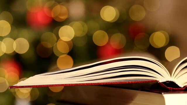 Open book on shimmering Christmas tree and garlands background.Christmas books. Winter books. 4k footage