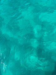 Fototapeta na wymiar Agua del mar cristalina en la orilla en tonos turquesas