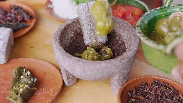 Preparation of traditional Mexican sauce in a molcajete with tomatoes, tomatoes, chilies, salt, onion and grasshoppers.