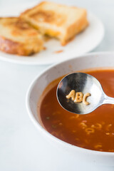 Alphabet soup with the letters A, B, C in the spoon and grilled cheese in behind