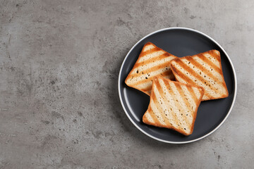 Plate with slices of delicious toasted bread on gray table, top view. Space for text