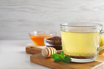 Cup of aromatic buckwheat tea, mint, honey and granules on white table, space for text