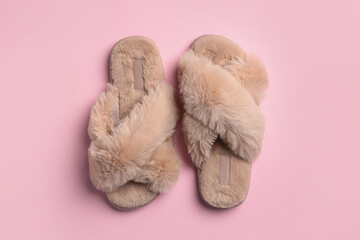 Fototapeta na wymiar Pair of soft fluffy slippers on pink background, top view