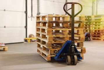 Modern manual forklift with wooden pallets in warehouse