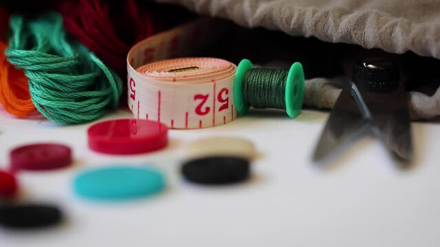 Close up of sewing supplies such as measuring tape, buttons, treads and scissors.