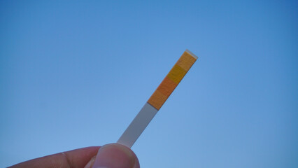 litmus paper on hand isolated on blue background. universal indicator paper with acidic testing - selective focus