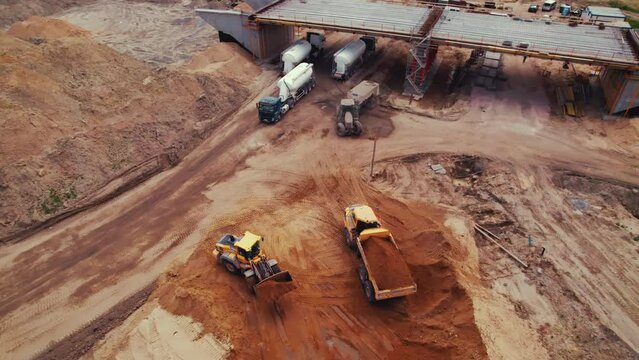 A bulldozer with a blade full of earth loading an industrial dumper truck on a highway construction site. Ground leveling. Warsaw, Poland. . High quality 4k footage