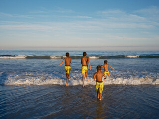 Four brothers heading into the surf in late afternoon lighting