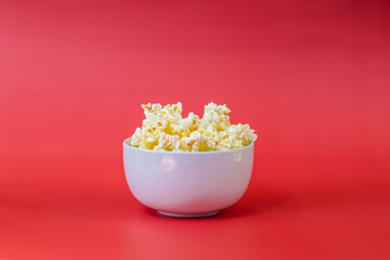 Popcorn in a white bowl on a red background