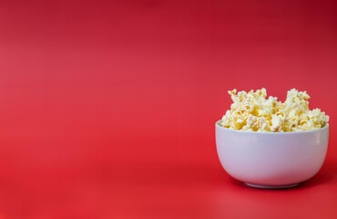 Popcorn in a white bowl on a red background, movie night