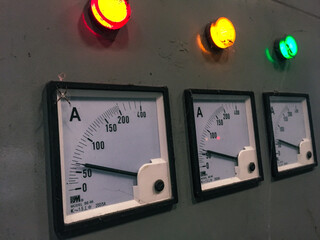 Industrial electrical panel with illuminated colored lights and numeric indicator needles - red, yello and green lamp. 