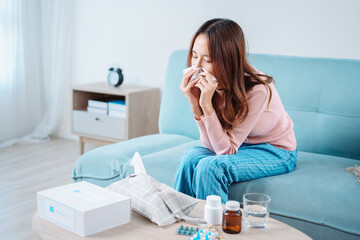 Asian young woman patient cold sick she sneeze with tissue paper on sofa, Female health problem blowing nose use pharmacy first aid box delivery service hospital, self recover health care concept.