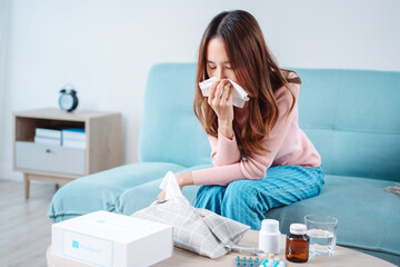 Asian young woman patient cold sick she sneeze with tissue paper on sofa, Female health problem...