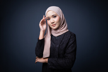 Portrait of a beautiful female model wearing hijab, a lifestyle apparel for Muslim women isolated on grey background. Idul Fitri and modern hijab fashion concept.