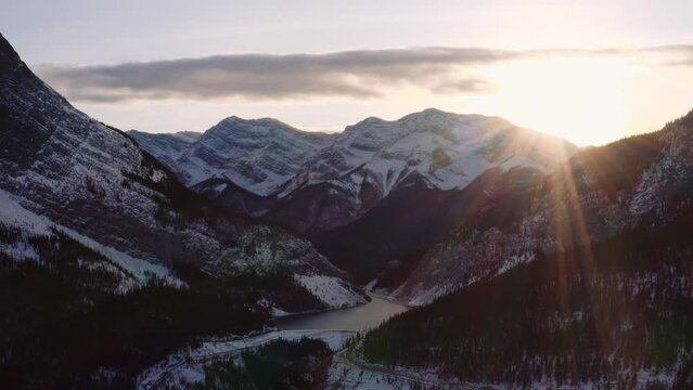 Slow lateral movement drone at sunset in Canadian rockies, lake is nestled amongst mountain tops.