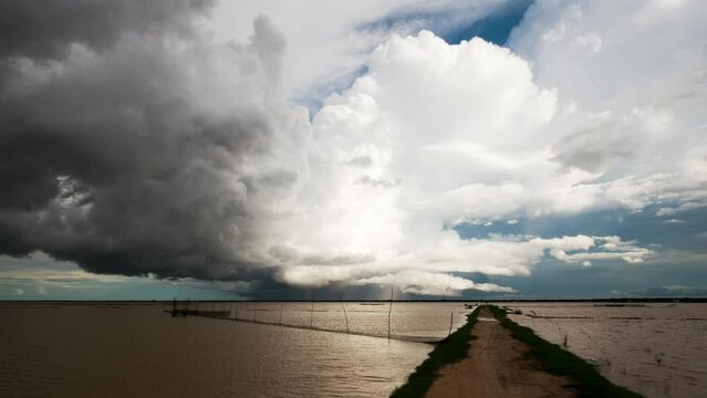 Low lying stormy weather front clouds rolling horizontally over the Tonle Sap lake with fish nets in foreground  and moving rain as the south east Asia monsoon season sets in.
