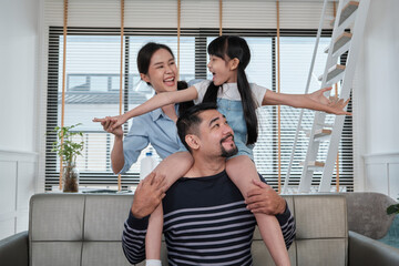 Asian Thai family together, dad plays and teases with daughter and mum by carrying and holding girl...