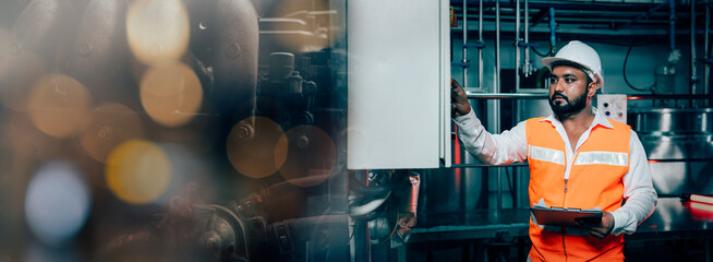 Professional engineering man in protective safety uniform with white hardhat working at factory,...