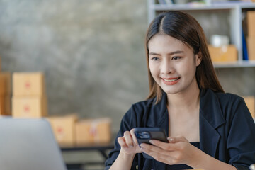 Fototapeta premium Beautiful Asian girl freelance SME business online shopping working on computer, laptop, smartphone with parcel box at home - online SME business idea and delivery.