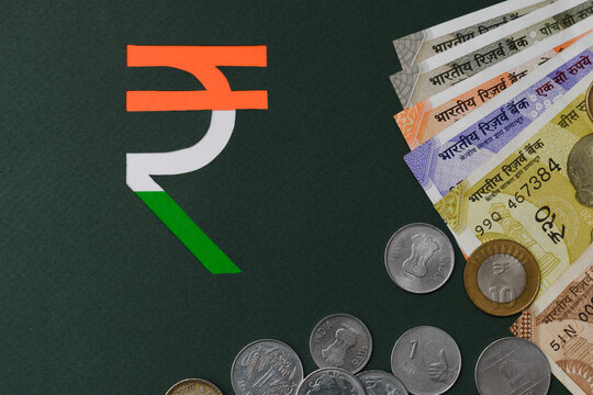 paper cut indian rupee symbol in tricolor with currency background. Flat lay, top view. 