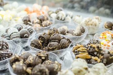 A collection of assorted chocolate candy balls in dishes on display