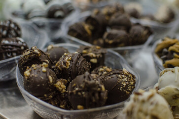 A collection of assorted chocolate candy balls in dishes on display