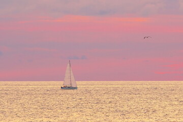 Fototapeta na wymiar Yacht in a calm sea. Beautiful sunset sky in pastel colors.