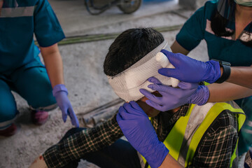 Paramedic first aid bandaging head to a man builder accident fall scaffolding to the floor at...