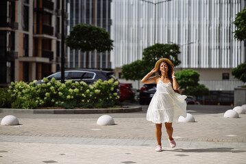 Beautiful pretty woman in white dress walking at city street