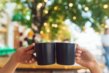 Closeup image of a people clinking coffee cups together in cafe