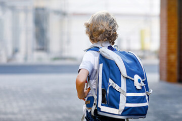 Happy little kid boy with backpack or satchel called Ranzen in German. Schoolkid on way to school....