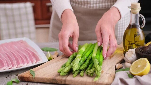 Cooking asparagus wrapped with bacon at domestic kitchen