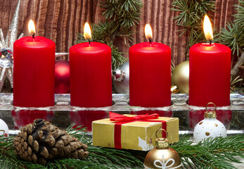 Red Christmas candles and Christmas gift boxes against wooden background