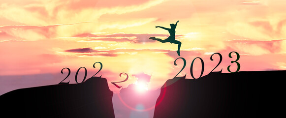 2023 Happy New Year concept, Young woman Jumping across the gap of the mountain from Old year 2022 to 2023 New Year.
                        