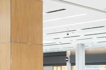 White Closed circuit television CCTV is hung on a white ceiling beside the air vents.